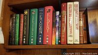 Books on shelf showing titles by Paolini including Eragon, Eldest, Brisingr, inheritance series and others