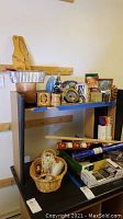 Photo of shelf with placed items including owl statue, pepper grinder, candles, and a basket full of various smaller items.