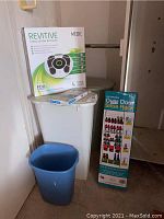 Lot contents including Revitive Circulation Booster box, two white hampers, blue waste bin, and Max Space shoe rack box.