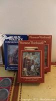 Three boxed ceramic decanters, two Norman Rockwell and one John Wayne, with original packaging visible.