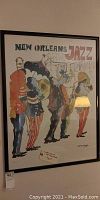 Framed full view of the colorful New Orleans Jazz Festival poster showing musicians in costume playing instruments.
