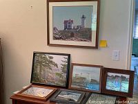 Full view of all seven framed photographs arranged on floor and wall showing variety of seascape and landscape images including Nubble Lighthouse, forest, seagulls, boats.