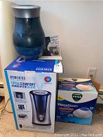 Homedics Total Comfort Humidifier Deluxe with blue humidifier on box and Vicks Warm Steam Vaporizer box visible on right side.