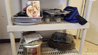 Photo showing shelves with multiple baking pans, muffin tins, and other items stacked.