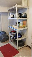 Wide view showing entire five-shelf plastic shelving unit filled with various household goods