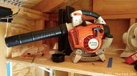 Side view of Stihl BG 86 gas blower with one extension tube attached, placed on a wooden shelf