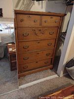 Front view of antique wooden dresser with six drawers, carved detailing, and metal handles.