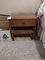 Overall view of first teak bedside table showing drawer, shelf and legs