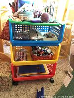 Photo of the 3-tier plastic rolling cart holding various sewing and craft supplies including spools of thread, pincushions, and other small notions.