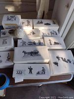 Overview of seven original Dept 56 Snow Village accessory boxes on a table, showing sketches of winter-themed figurines on lids.
