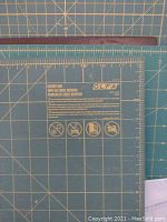 Cutting mat close-up showing Olfa RM-CG 9680 model and grid markings