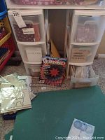 Six plastic storage bins filled with quilting fabrics and materials. Binders and quilting magazines are also included in the lot.