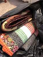 Folded quilts stacked in a bag showing colorful and patterned fabrics.