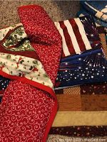 View of three quilts stacked showing red swirling vine pattern, patriotic colors with stars and stripes, and brown/orange patchwork.