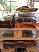 Five plastic storage containers stacked, filled with sewing and crafting supplies including labeled fabric pieces.