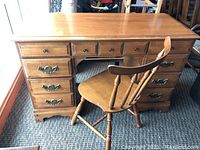 Full front view of solid lightwood desk paired with wooden chair, showing surface and drawer layout.