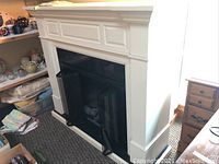 Front view of white mantel surrounding black fireplace insert with glass doors open.