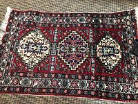 Close-up view showing the detailed geometric and floral design of the rug with red, white, and blue colors.