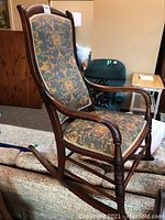 Side angle view of vintage rocking chair showing the frame and upholstery fabric pattern.