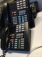 Four black Meridian EXT 230 desk phones positioned together showing front keypad and display layouts.
