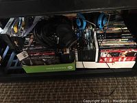 Photo showing collection of DVDs and headsets organized on a shelf including boxed DVDs and headsets with wires visible.