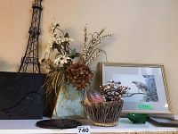 Overall display of the lot items including Robert Bateman print, metal vase with faux flowers, dragon eggs in basket, and wooden trivet on table under wall-hanging Eiffel Tower art.