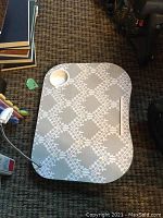 Photo of a floral patterned laptop lap desk with built-in reading light and cup holder, on carpet
