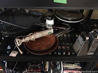 Kitchen items on shelves including Crock Pot, frypans, hand mixer, fish grill, and cheese graters