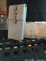 Side view of light blue travel purse with buckle detail