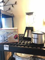 Photo showing box and assembled pasta maker, blender, and heating pot on shelf.