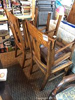 Four solid oak chairs stacked, showing structure and wood grain.