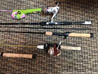 Photo showing five fishing rods laid out on carpet, displaying varied handle types and reel attachments, including a casting reel and a spinning reel.