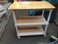 Front view of the tea cart showing natural wood top, painted white legs, two lower shelves, and wheels.