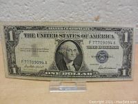 Front view of the 1957 Silver Certificate one dollar note showing serial number, portrait of George Washington, and blue Treasury seal.