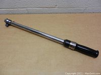 Full view of the Husky 20-inch chrome torque wrench with black handle on a tan surface.