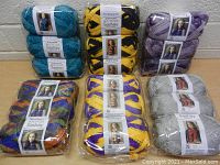 Photo shows 18 skeins arranged in groups by color: teal blue, black/yellow, purple, multi-color, bright yellow/purple, and light gray. All skeins are Red Heart Sashay yarn.
