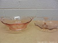 Wide view of both vintage pink glass pieces side by side on a table, showing the bowl and cake stand.