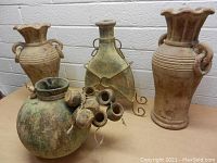 Photo showing all five decorative clay pottery pieces with varied shapes and patinas