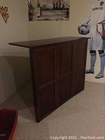Front and side view of the wooden bar cabinet showing panel detailing and dark finish