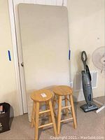 Photo of the full catering table top and one stool leaning against a wall in a carpeted basement room.