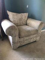 Front view of beige upholstered armchair with patterned fabric, showing large back cushion and wide armrests.