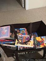 Photo of a large brown tote bag filled with various DVDs, view of DVD cases disabled inside with visible cover art from titles such as Glee, Uncle Buck, and others