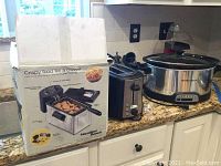 Hamilton Beach deep fryer on countertop with original box, next to Amazon Basics toaster and Hamilton Beach slow cooker