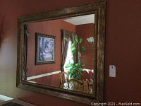 Full view of large rectangular framed mirror reflecting a dining area and window.