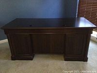 Full frontal view of the Sauder desk showing dark wood finish and rectangular top with inset access holes.