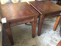 Pair of wooden side tables placed side by side, showing tops and legs with visible scratches and discoloration on one table.