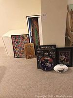 Full view of the sports memorabilia lot showing framed pictures, signed football, clock, and bar signs.