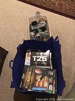 Two silver GameCube controllers and assorted cables in plastic container