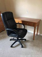 Photo of black office chair in front of wooden desk showing chair and desk dimensions and condition
