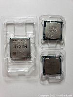 Three processors side by side in clamshell trays on white surface